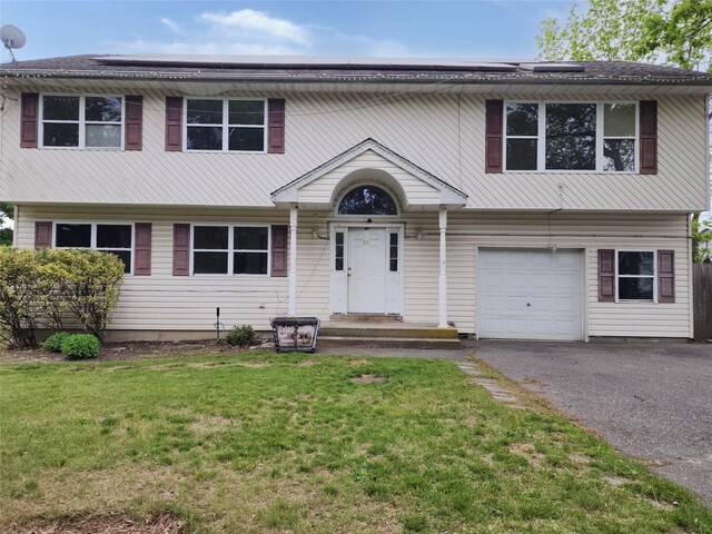 36 S 23rd St, Wyandanch, NY 11798 - view of front of home with a front yard, a garage, driveway, and roof mounted solar panels