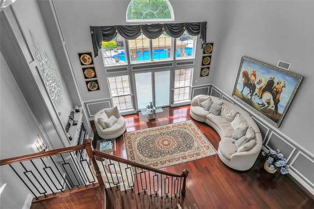 8 Wisteria Ln, Lake Grove, NY 11755 - living area featuring wood finished floors, a towering ceiling, wainscoting, a decorative wall, and stairs