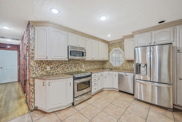 8 Adolphi Pl, Ronkonkoma, NY 11779 - kitchen featuring appliances with stainless steel finishes, a textured ceiling, light tile patterned flooring, tasteful backsplash, and light stone counters