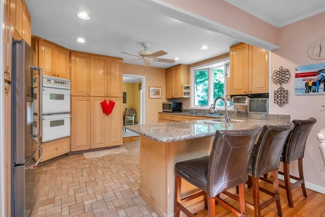 26 Mayberry Rd, Chappaqua, NY 10514 - kitchen featuring stainless steel appliances, a sink, a peninsula, a breakfast bar area, and light stone countertops