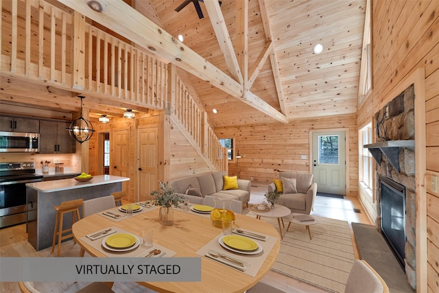 57 Zane Grey Way, Barryville, NY 12719 - dining area with a wood ceiling with exposed beams, wood walls, a stone fireplace, light wood-type flooring, and high vaulted ceiling