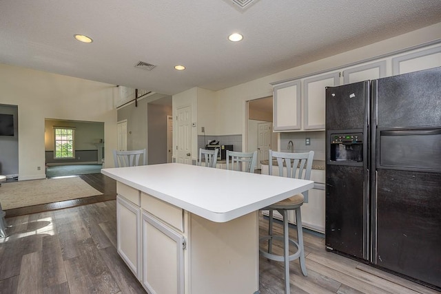 20 Hawk Nest Rd, Tomkins Cove, NY 10986 - kitchen featuring black fridge with ice dispenser, a center island, wood finished floors, a kitchen breakfast bar, and light countertops