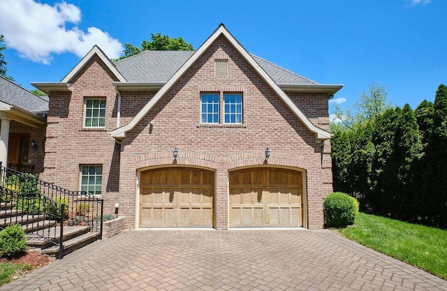 23 Tanners Rd, Great Neck, NY 11020 - tudor-style house with an attached garage, decorative driveway, brick siding, and roof with shingles