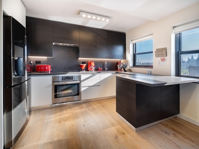 25-40 Shore Blvd Unit 17K, Astoria, NY 11102 - kitchen featuring oven, fridge with ice dispenser, modern cabinets, light wood-type flooring, and exhaust hood