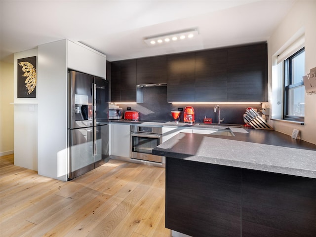 25-40 Shore Blvd Unit 17K, Astoria, NY 11102 - kitchen with stainless steel appliances, light wood finished floors, a peninsula, decorative backsplash, and modern cabinets