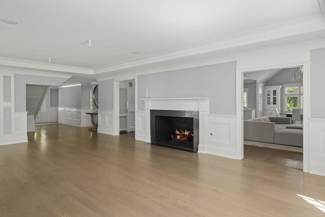8 E Huxley Dr, Lloyd Harbor, NY 11743 - unfurnished living room with a decorative wall, a lit fireplace, crown molding, wood finished floors, and stairs