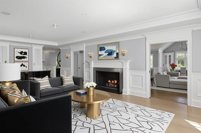 8 E Huxley Dr, Lloyd Harbor, NY 11743 - living area with a decorative wall, a lit fireplace, light wood-style flooring, crown molding, and a wainscoted wall