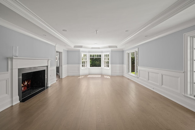 8 E Huxley Dr, Lloyd Harbor, NY 11743 - unfurnished living room featuring a tray ceiling, a lit fireplace, wood finished floors, a wainscoted wall, and ornamental molding