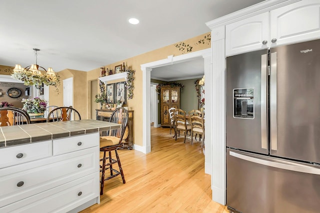 258 Timberpoint Rd, East Islip, NY 11730 - kitchen featuring stainless steel refrigerator with ice dispenser, tile counters, a chandelier, light wood-style floors, and white cabinetry