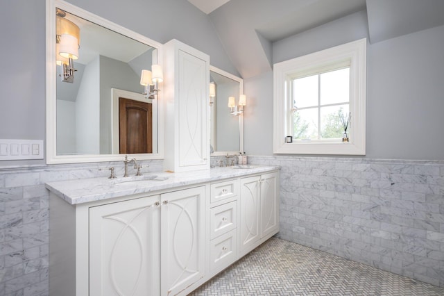 24 The Pnes, Old Westbury, NY 11568 - full bathroom featuring tile walls, wainscoting, double vanity, tile patterned floors, and vaulted ceiling