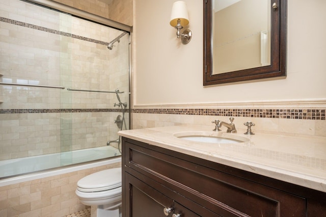 24 The Pnes, Old Westbury, NY 11568 - full bath featuring tiled shower / bath, tile walls, toilet, vanity, and wainscoting