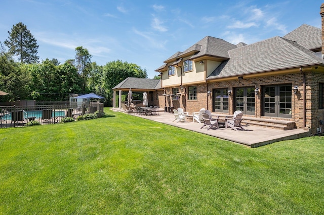 24 The Pnes, Old Westbury, NY 11568 - back of property featuring a patio area, roof with shingles, brick siding, and a fire pit