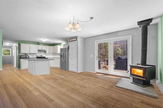 916 Queens Hwy, Accord, NY 12404 - kitchen with stainless steel fridge with ice dispenser, under cabinet range hood, a wood stove, white cabinetry, and light wood-style floors