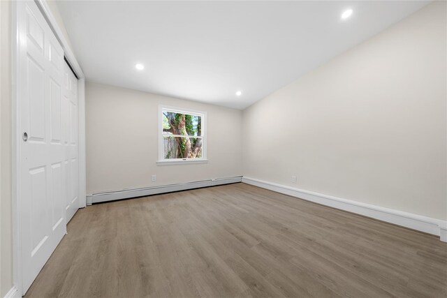 28 Snowberry Ln, Islandia, NY 11749 - unfurnished bedroom featuring wood finished floors, a baseboard heating unit, recessed lighting, and a closet