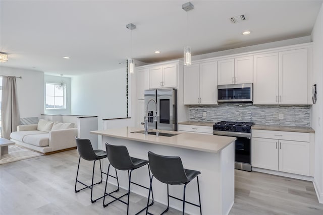 12 Grace Hall Ln, Yaphank, NY 11980 - kitchen featuring stainless steel appliances, a sink, tasteful backsplash, a kitchen breakfast bar, and light wood finished floors