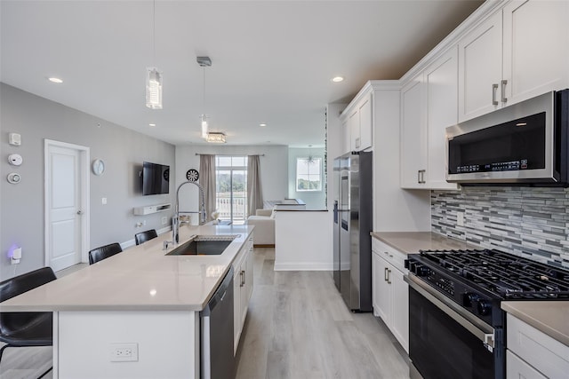 12 Grace Hall Ln, Yaphank, NY 11980 - kitchen featuring appliances with stainless steel finishes, a sink, open floor plan, light wood-style flooring, and tasteful backsplash