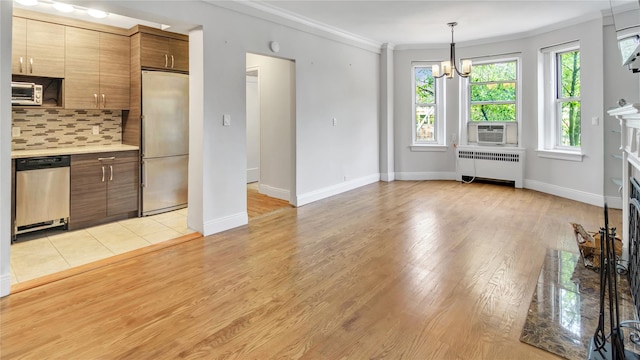 8 Barstow Rd Unit 2G, Great Neck, NY 11021 - kitchen featuring appliances with stainless steel finishes, radiator, crown molding, tasteful backsplash, and light countertops