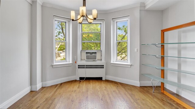8 Barstow Rd Unit 2G, Great Neck, NY 11021 - dining space with radiator heating unit, a chandelier, ornamental molding, wood finished floors, and baseboards