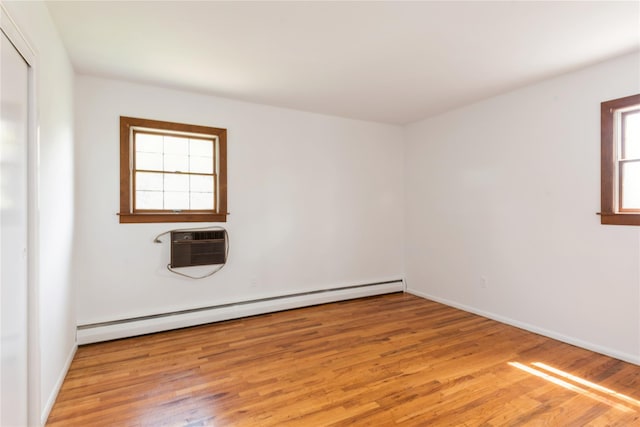 233 Violet St, Massapequa Park, NY 11762 - spare room with baseboard heating, light wood-type flooring, an AC wall unit, and baseboards