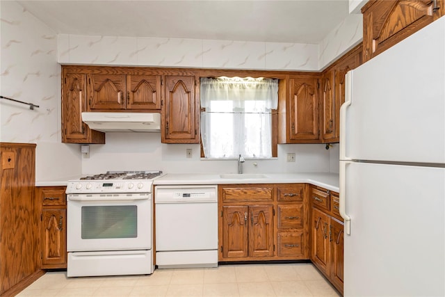 1649 Falmouth Ave, New Hyde Park, NY 11040 - kitchen with white appliances, under cabinet range hood, a sink, brown cabinets, and light countertops