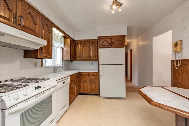 1649 Falmouth Ave, New Hyde Park, NY 11040 - kitchen with white appliances, a sink, under cabinet range hood, and brown cabinetry