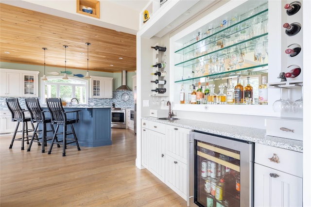 2335 Minnehaha Blvd, Southold, NY 11971 - indoor wet bar with wine cooler, stainless steel range oven, wall chimney exhaust hood, tasteful backsplash, and light wood-style floors