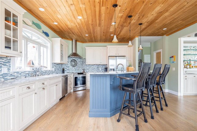 2335 Minnehaha Blvd, Southold, NY 11971 - kitchen with stainless steel appliances, wall chimney exhaust hood, light wood-style floors, decorative backsplash, and wood ceiling