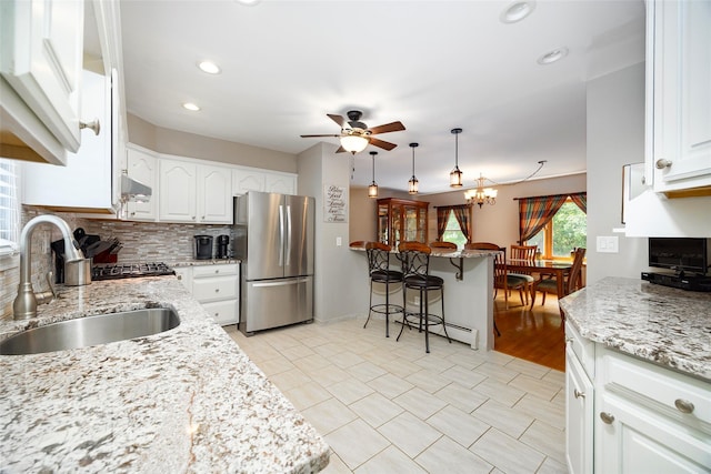 23 Saddle Rock Dr, Poughkeepsie, NY 12603 - kitchen with freestanding refrigerator, a sink, a ceiling fan, a kitchen breakfast bar, and backsplash
