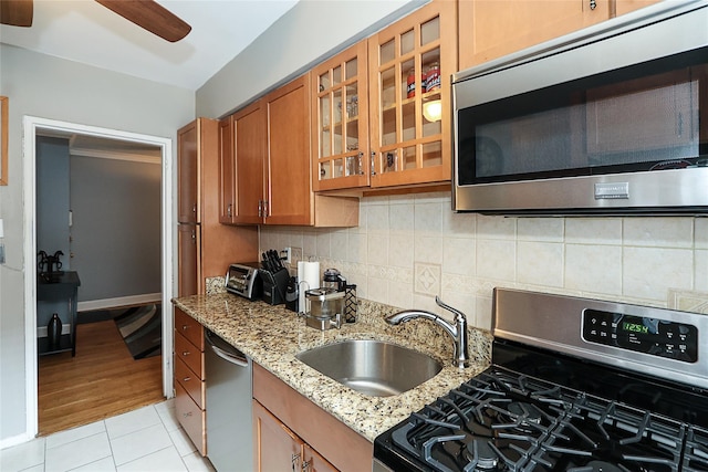 200 N Village Ave Unit D5, Rockville Centre, NY 11570 - kitchen with appliances with stainless steel finishes, brown cabinets, a sink, light tile patterned floors, and glass insert cabinets