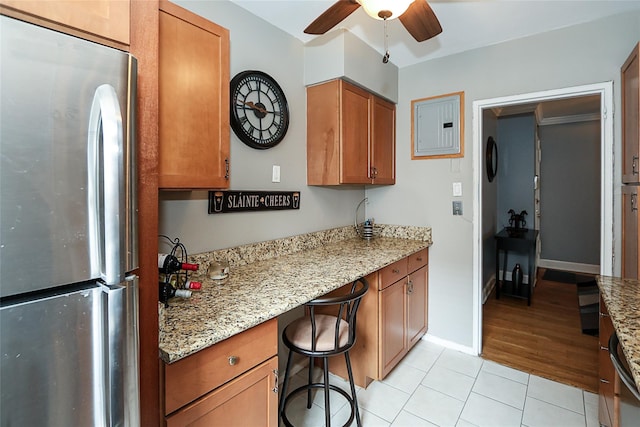200 N Village Ave Unit D5, Rockville Centre, NY 11570 - kitchen with freestanding refrigerator, brown cabinets, a ceiling fan, electric panel, and light stone countertops