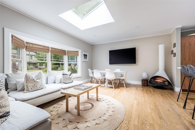 21 Hillside Dr W, Sag Harbor, NY 11963 - living room with light wood-style floors, baseboards, crown molding, a skylight, and a wood stove