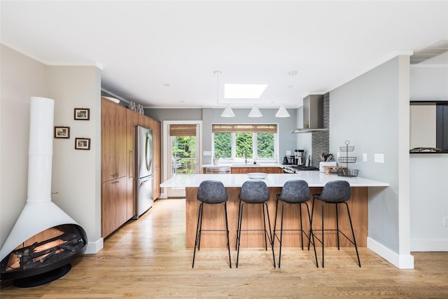 21 Hillside Dr W, Sag Harbor, NY 11963 - kitchen with freestanding refrigerator, a peninsula, wall chimney exhaust hood, light wood-type flooring, and light countertops