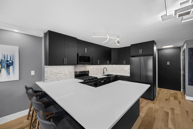 345 E 93rd St Unit 25Ak, New York Manhattan, NY 10128 - kitchen featuring appliances with stainless steel finishes, dark cabinets, light countertops, a peninsula, and a sink