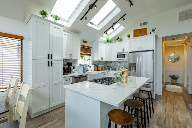 29 Mckinley Ave, Lindenhurst, NY 11757 - kitchen with a skylight, appliances with stainless steel finishes, light wood-type flooring, a breakfast bar, and white cabinets