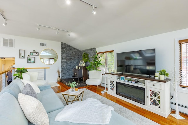 29 Mckinley Ave, Lindenhurst, NY 11757 - living area featuring rail lighting, wood finished floors, a wood stove, healthy amount of natural light, and vaulted ceiling