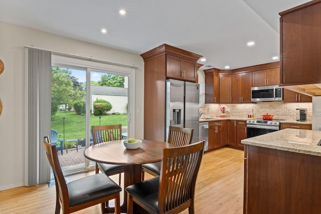12 Franklin Commons, Yaphank, NY 11980 - kitchen with stainless steel appliances, a sink, backsplash, light wood-style flooring, and light stone counters