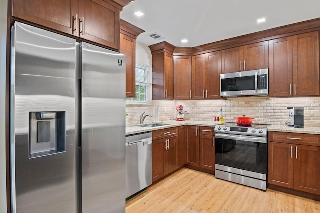 12 Franklin Commons, Yaphank, NY 11980 - kitchen featuring stainless steel appliances, light wood-style floors, light stone countertops, tasteful backsplash, and a sink