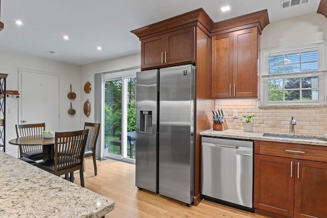 12 Franklin Commons, Yaphank, NY 11980 - kitchen featuring stainless steel appliances, a sink, light wood-style flooring, tasteful backsplash, and light stone countertops