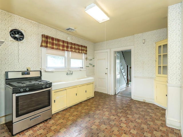 3 3rd St, Glenwood Landing, NY 11547 - kitchen featuring stainless steel gas stove, wallpapered walls, light countertops, a sink, and brick patterned flooring