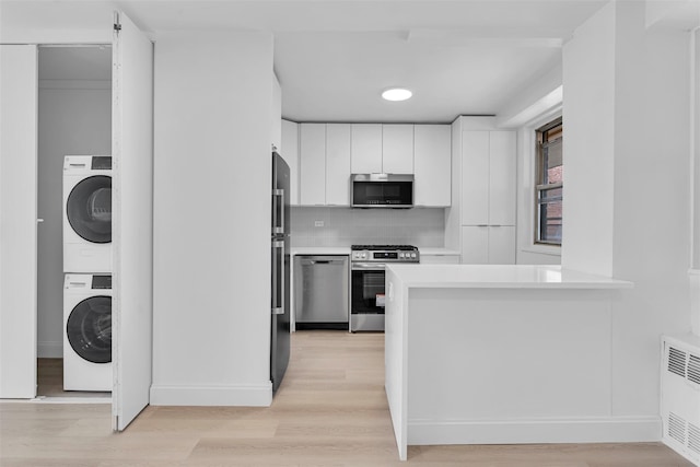 5700 Arlington Ave Unit 20K, Bronx, NY 10471 - kitchen featuring appliances with stainless steel finishes, stacked washer / drying machine, light wood-type flooring, light countertops, and white cabinets