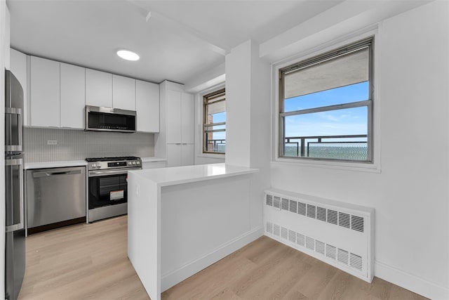 5700 Arlington Ave Unit 20K, Bronx, NY 10471 - kitchen featuring radiator heating unit, appliances with stainless steel finishes, white cabinets, light wood-type flooring, and light countertops