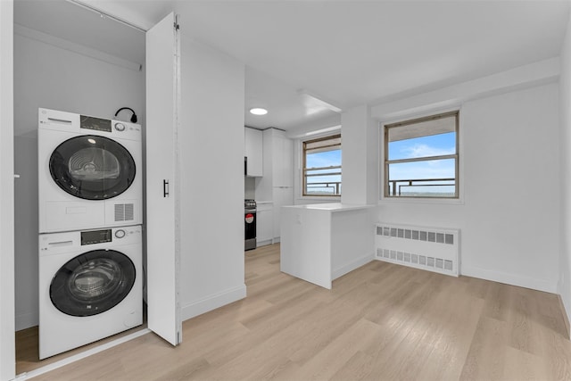 5700 Arlington Ave Unit 20K, Bronx, NY 10471 - washroom with radiator heating unit, stacked washer / dryer, light wood finished floors, and baseboards