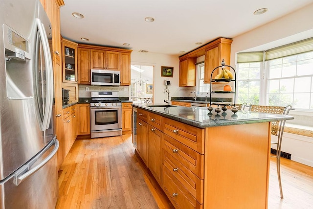 21 Maple Rd, Setauket, NY 11733 - kitchen with stainless steel appliances, decorative backsplash, light wood-type flooring, a breakfast bar, and brown cabinets