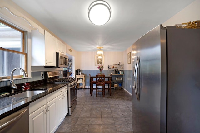 106 S Country Rd, Westhampton Beach, NY 11978 - kitchen with stainless steel appliances, a sink, white cabinetry, and dark stone countertops