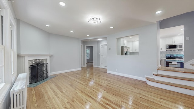 596 Terrace Pl, Baldwin, NY 11510 - unfurnished living room featuring light wood-style flooring, a fireplace, radiator, baseboards, and recessed lighting