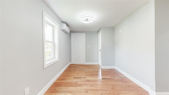 596 Terrace Pl, Baldwin, NY 11510 - spare room with a wall unit AC, light wood-style floors, and baseboards