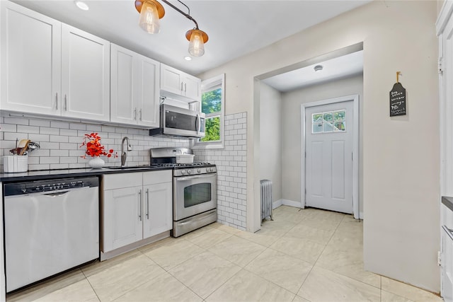 70-27 Olcott St, Forest Hills, NY 11375 - kitchen with appliances with stainless steel finishes, radiator, healthy amount of natural light, and white cabinets