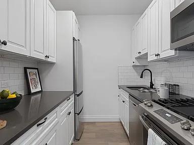 4035 Ithaca St Unit 6F, Elmhurst, NY 11373 - kitchen with stainless steel appliances, a sink, dark countertops, white cabinets, and tasteful backsplash
