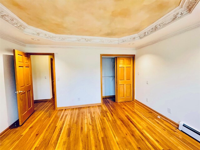 24 Gaymor Ln, Commack, NY 11725 - unfurnished bedroom featuring baseboard heating, a tray ceiling, baseboards, crown molding, and light wood-style floors