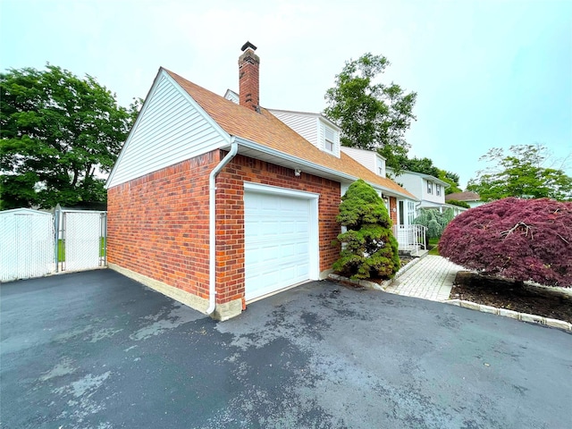 24 Gaymor Ln, Commack, NY 11725 - view of side of home featuring brick siding, an attached garage, a gate, asphalt driveway, and a chimney